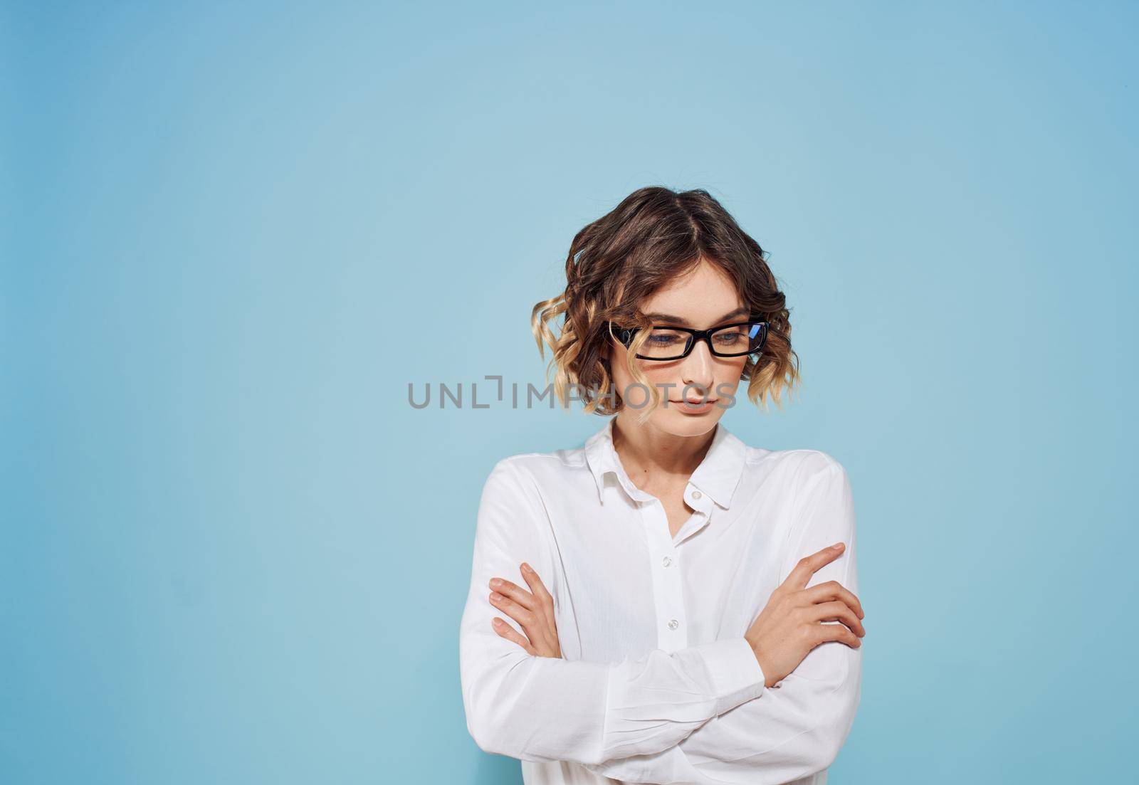 Fashionable woman with short hair and glasses white shirt blue background. High quality photo