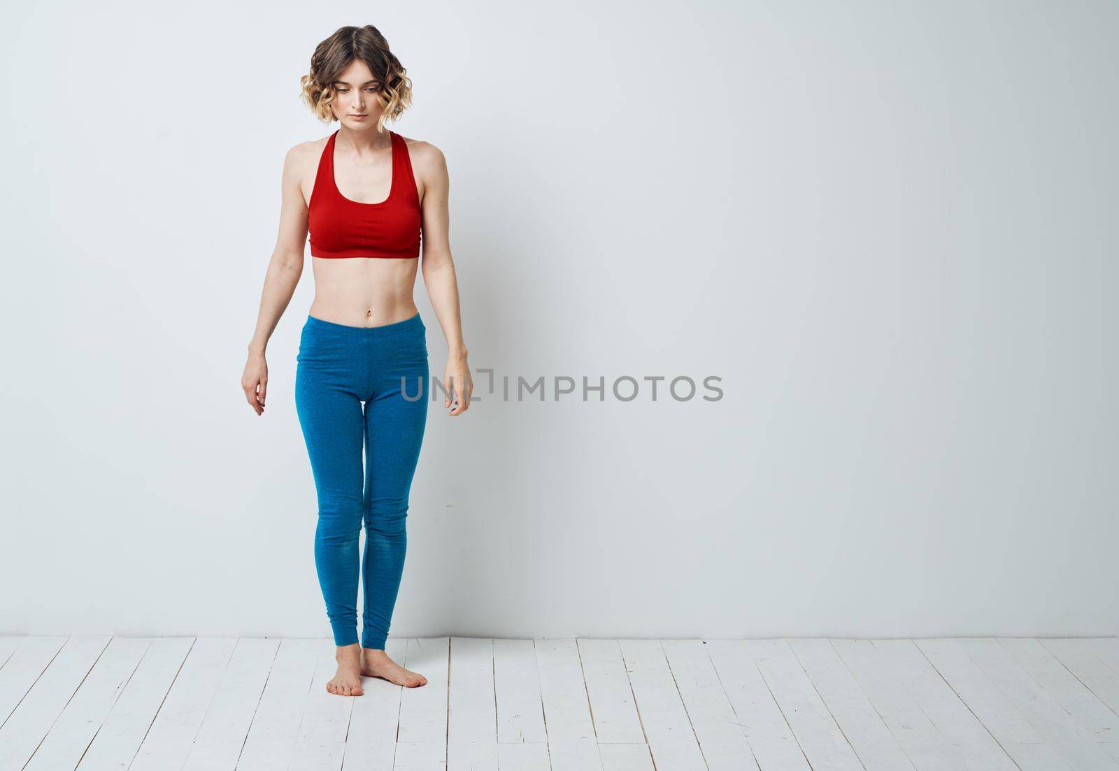 woman in blue leggings doing sports on a light floor indoors in full growth. High quality photo