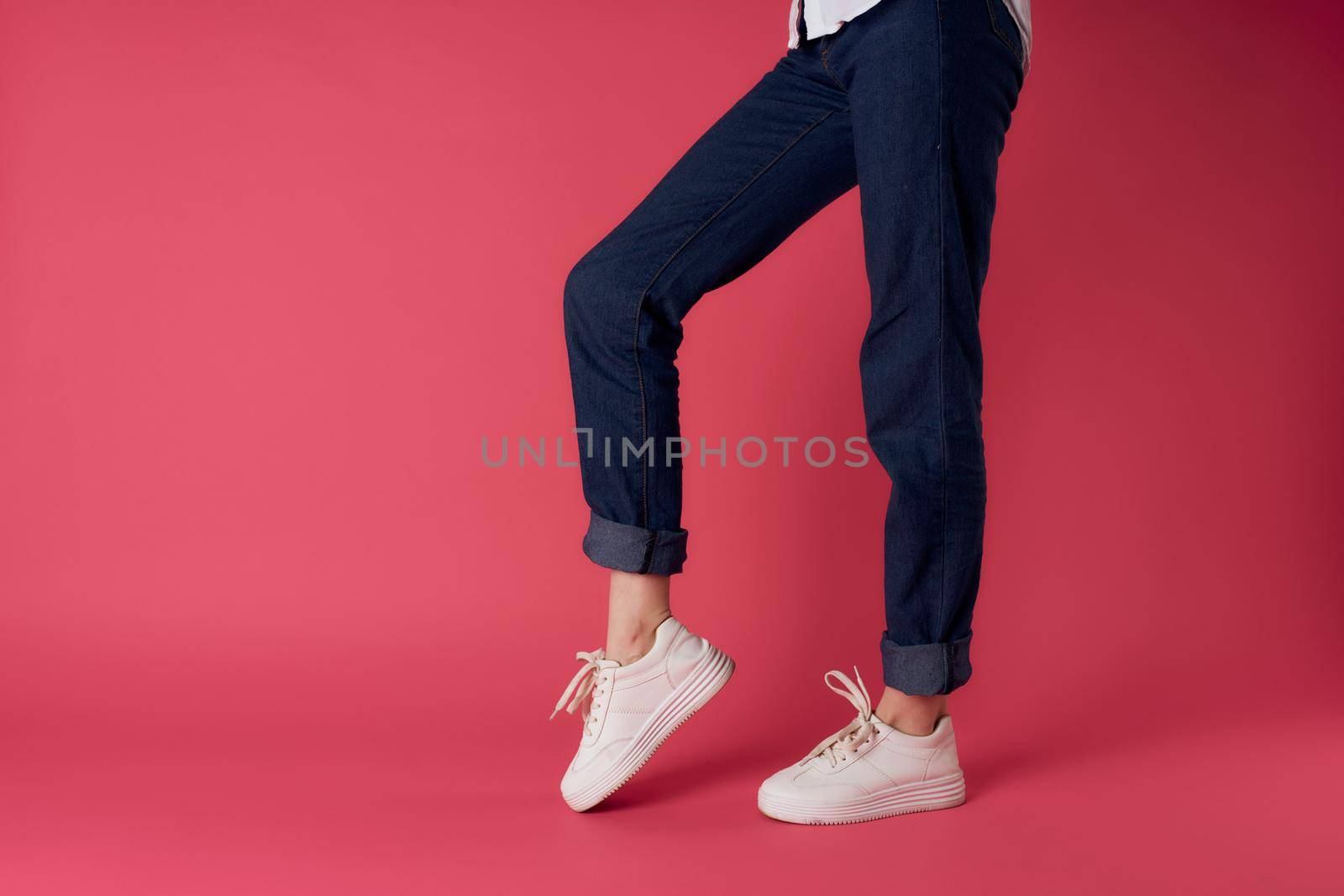 Womens feet white sneakers fashion street style pink background. High quality photo