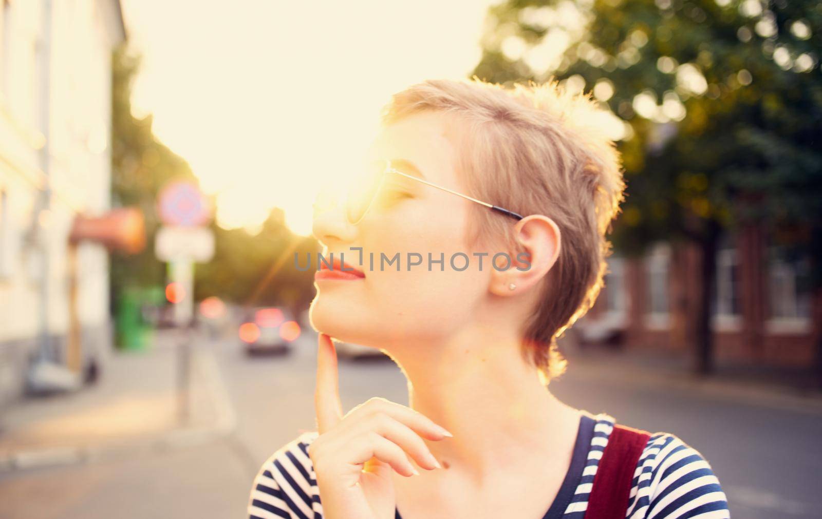 romantic woman in a sundress and red glasses walks along the city street in summer. High quality photo