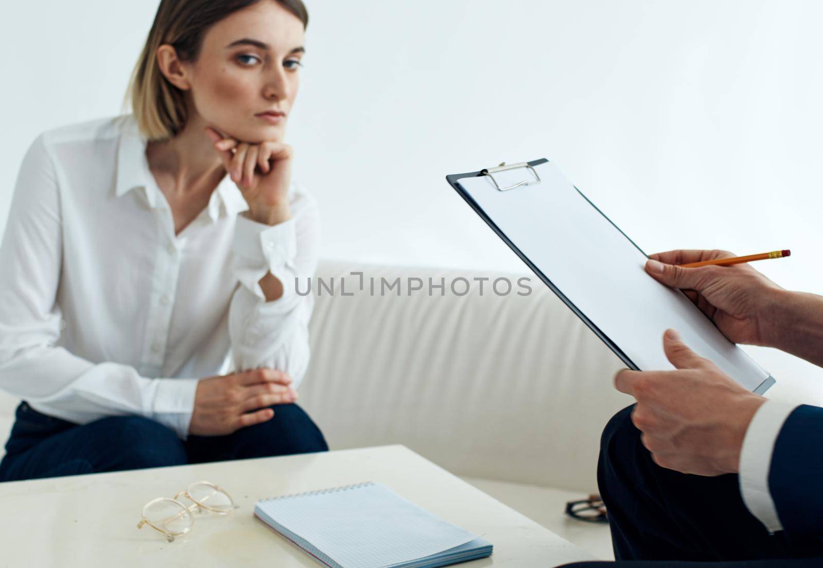 A man with documents and a woman on the couch at the table indoors staff psychologist reception doctor. High quality photo