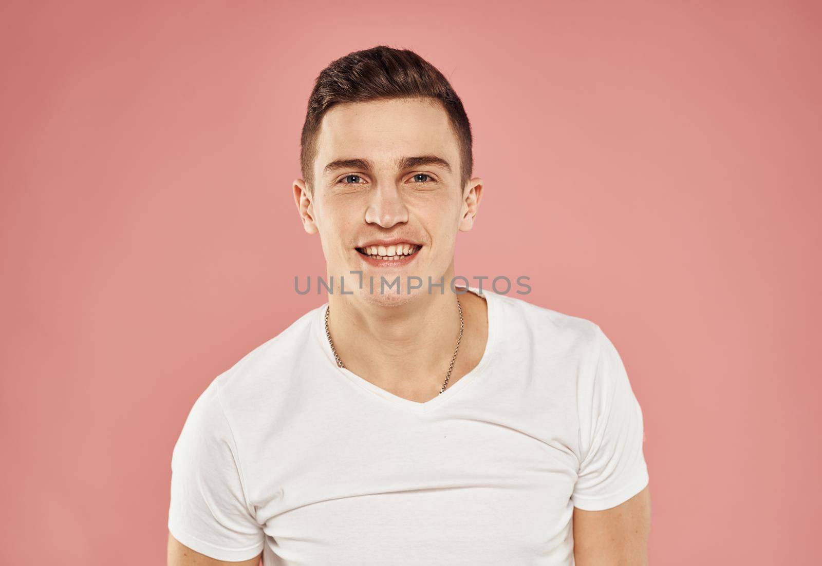 handsome man in white t-shirt emotions joy pink background. High quality photo