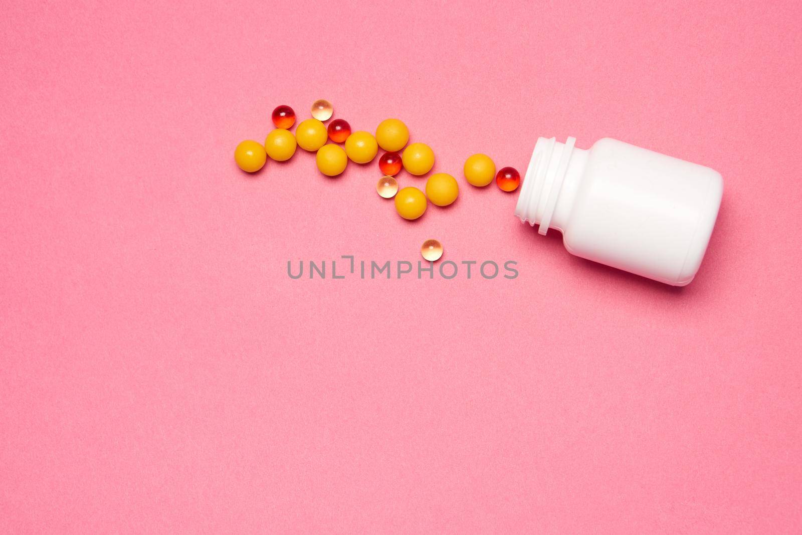 Open jar with pills on pink background coldspace top view. High quality photo