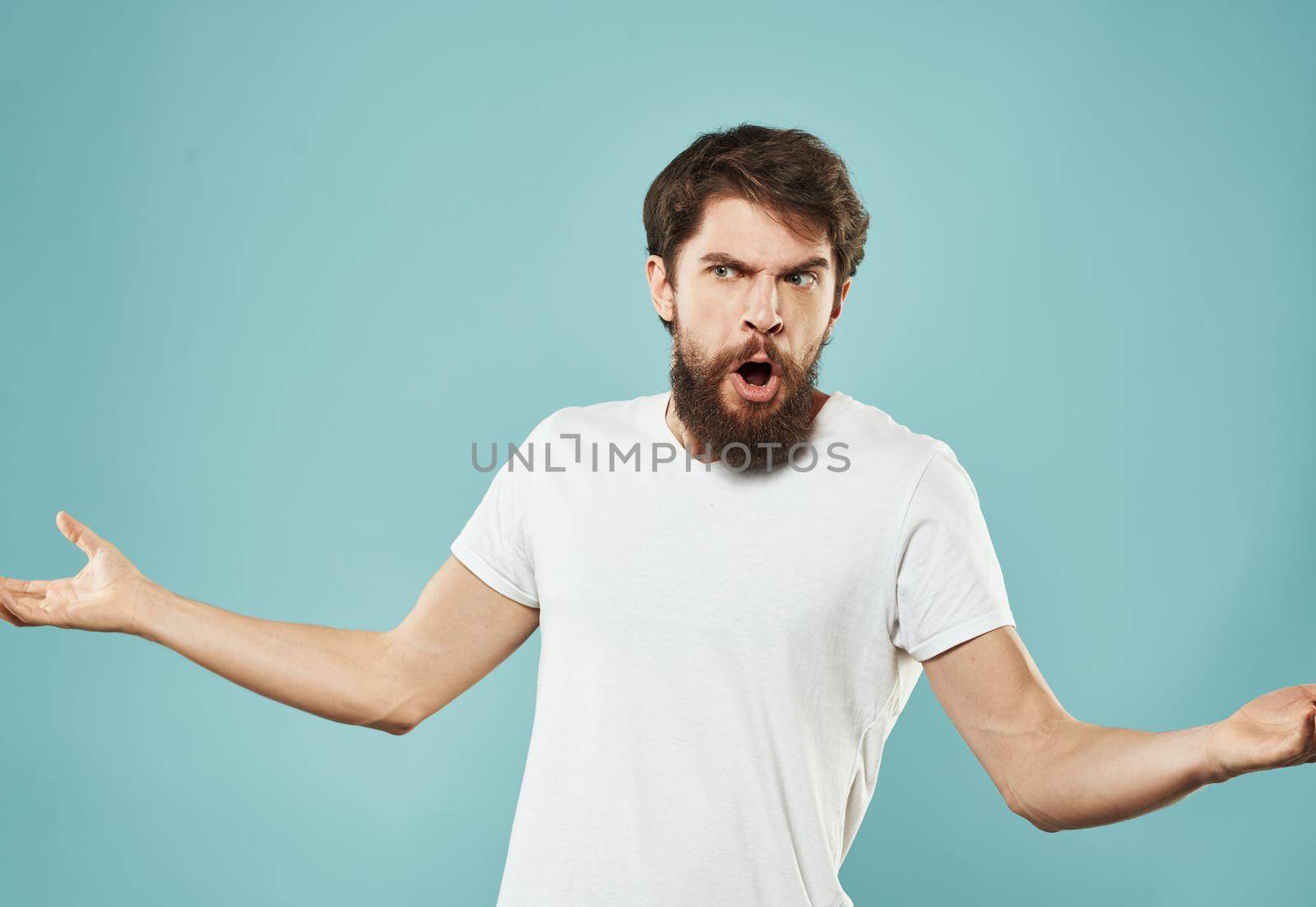 Angry guy gesturing with his hands on a blue background cropped with Copy Space. High quality photo