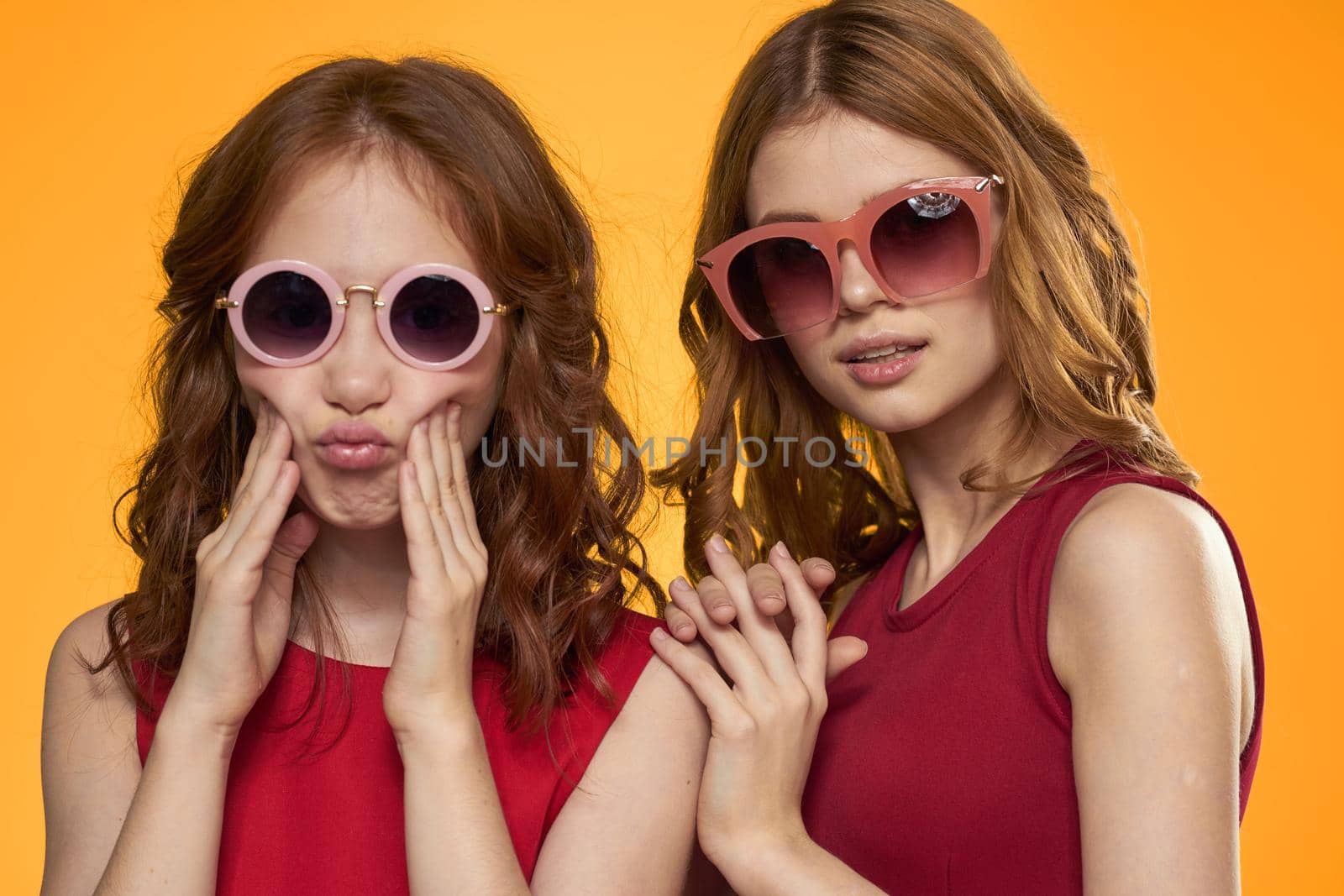 cheerful mom and daughter wearing sunglasses lifestyle friendship family yellow background studio. High quality photo