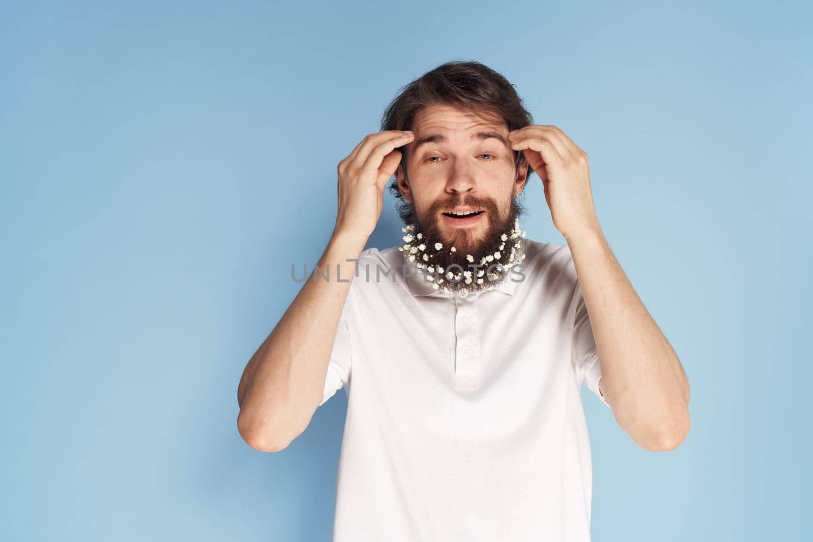 Cheerful car white T-shirt flowers in a beard close-up blue background. High quality photo
