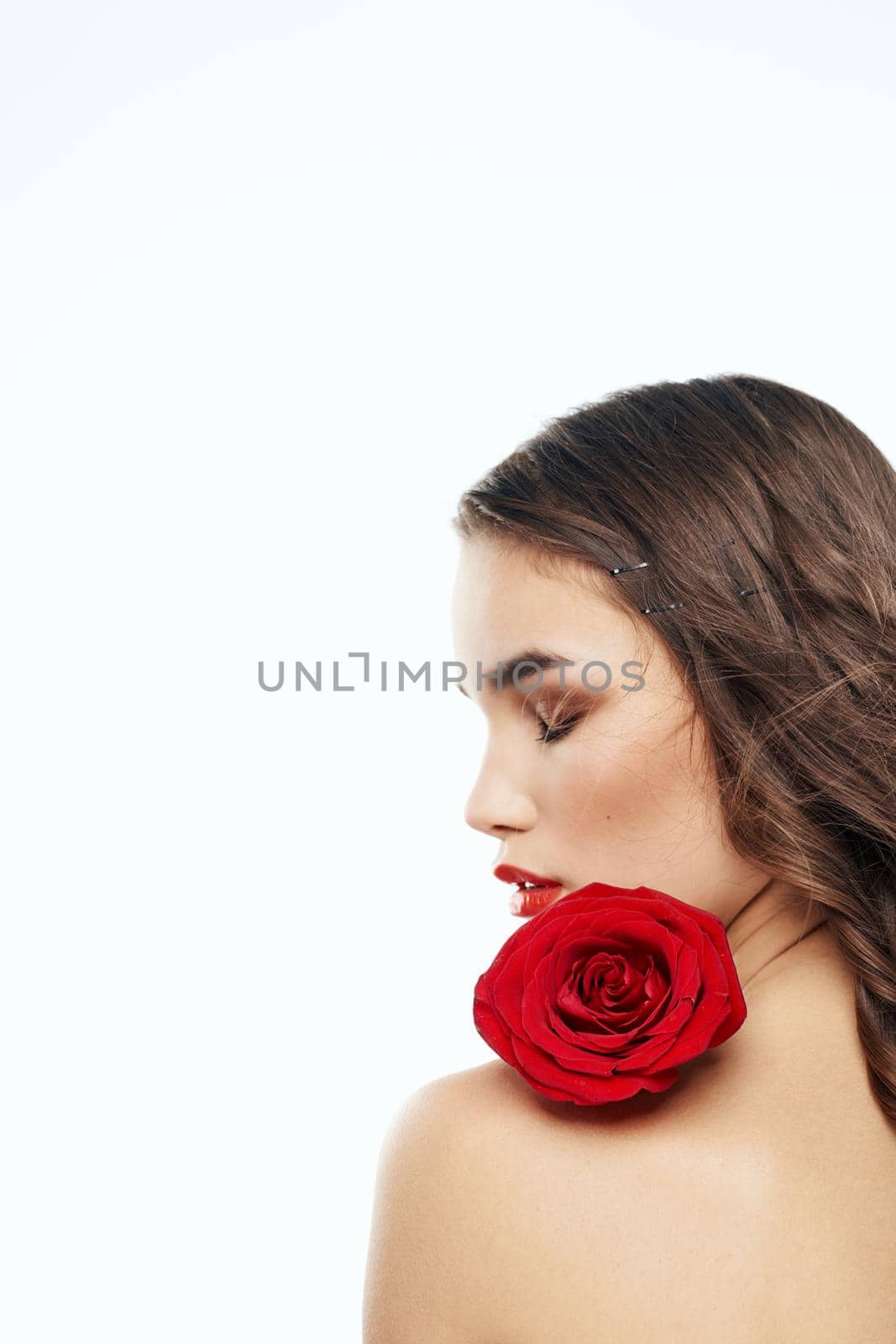 Back view of attractive brunette with red rose on naked shoulder. High quality photo