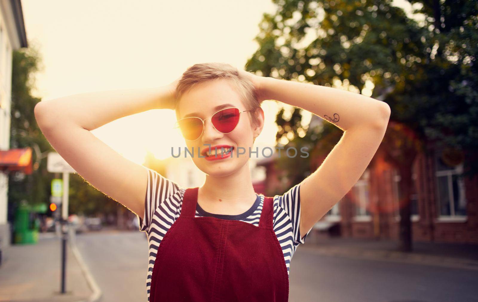 romantic woman in a sundress and red glasses walks along the city street in summer. High quality photo