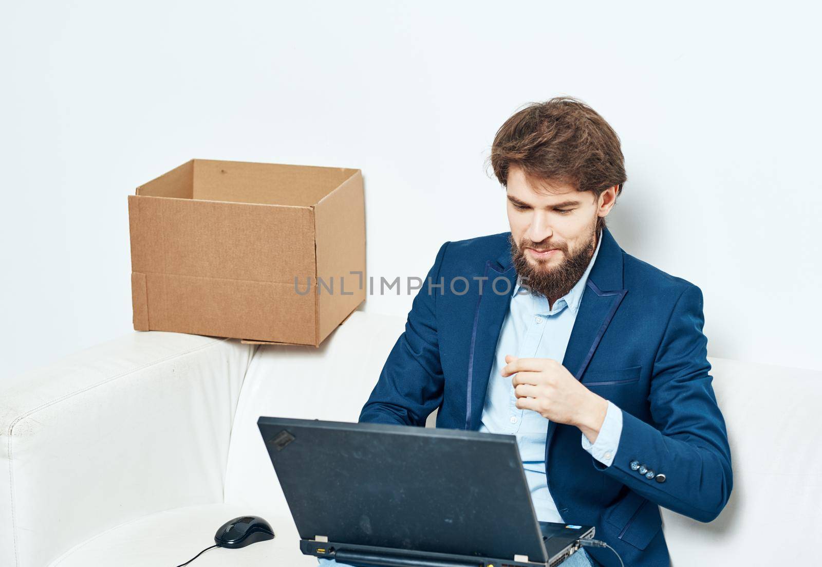 Manager sits on the couch with a laptop working professional boxes with things by SHOTPRIME