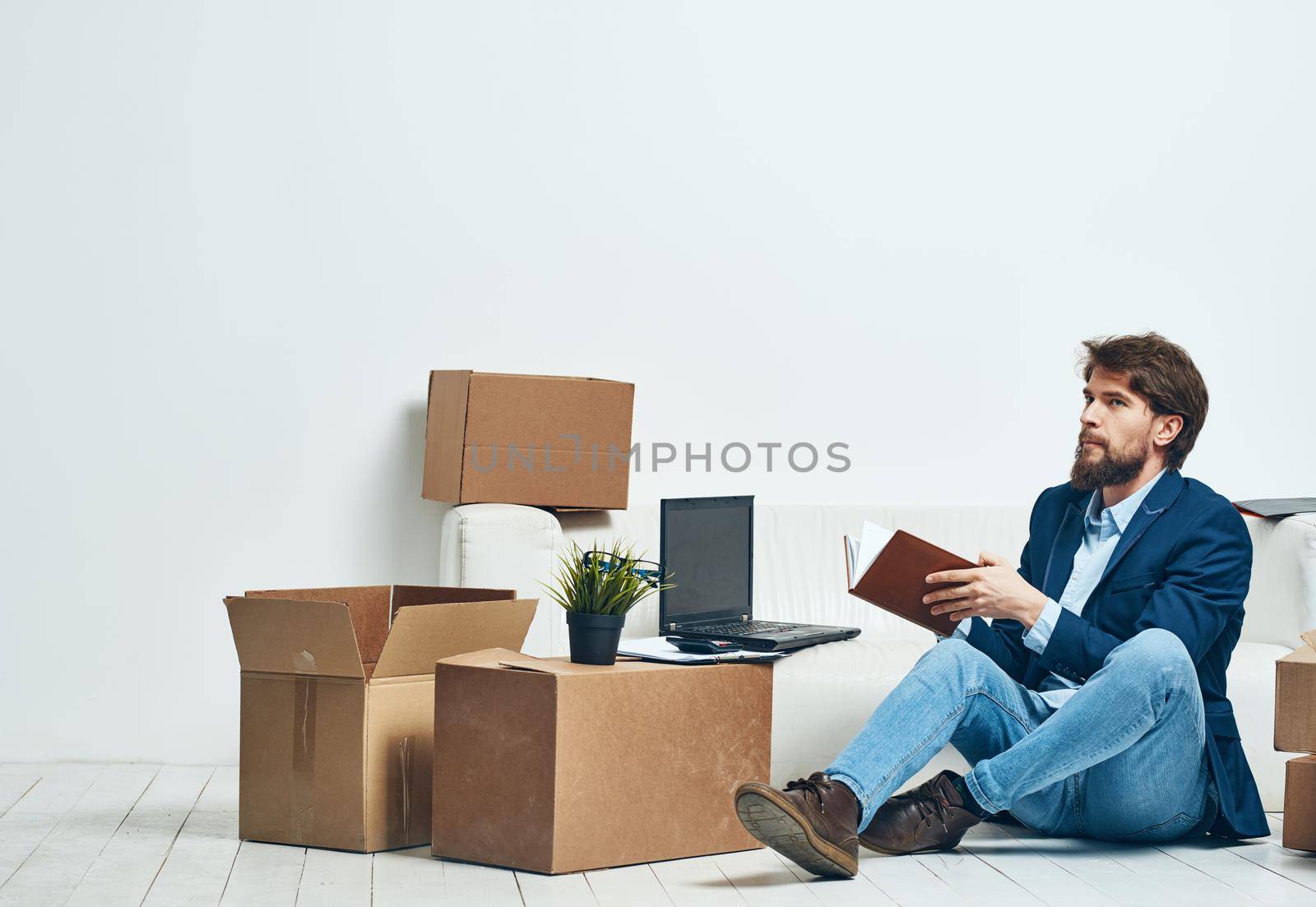 A man sits on the floor of a box with things office moving unpacking official. High quality photo