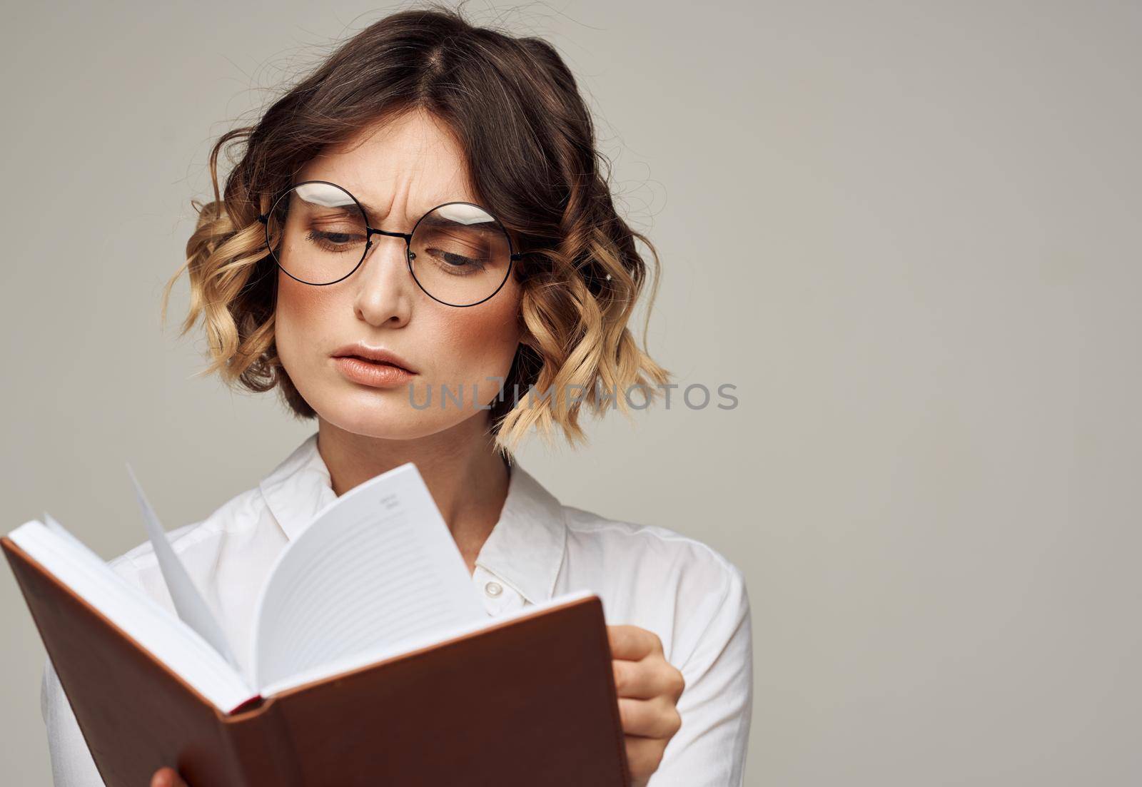 Literate woman with book in hands and in glasses white shirt education model. High quality photo