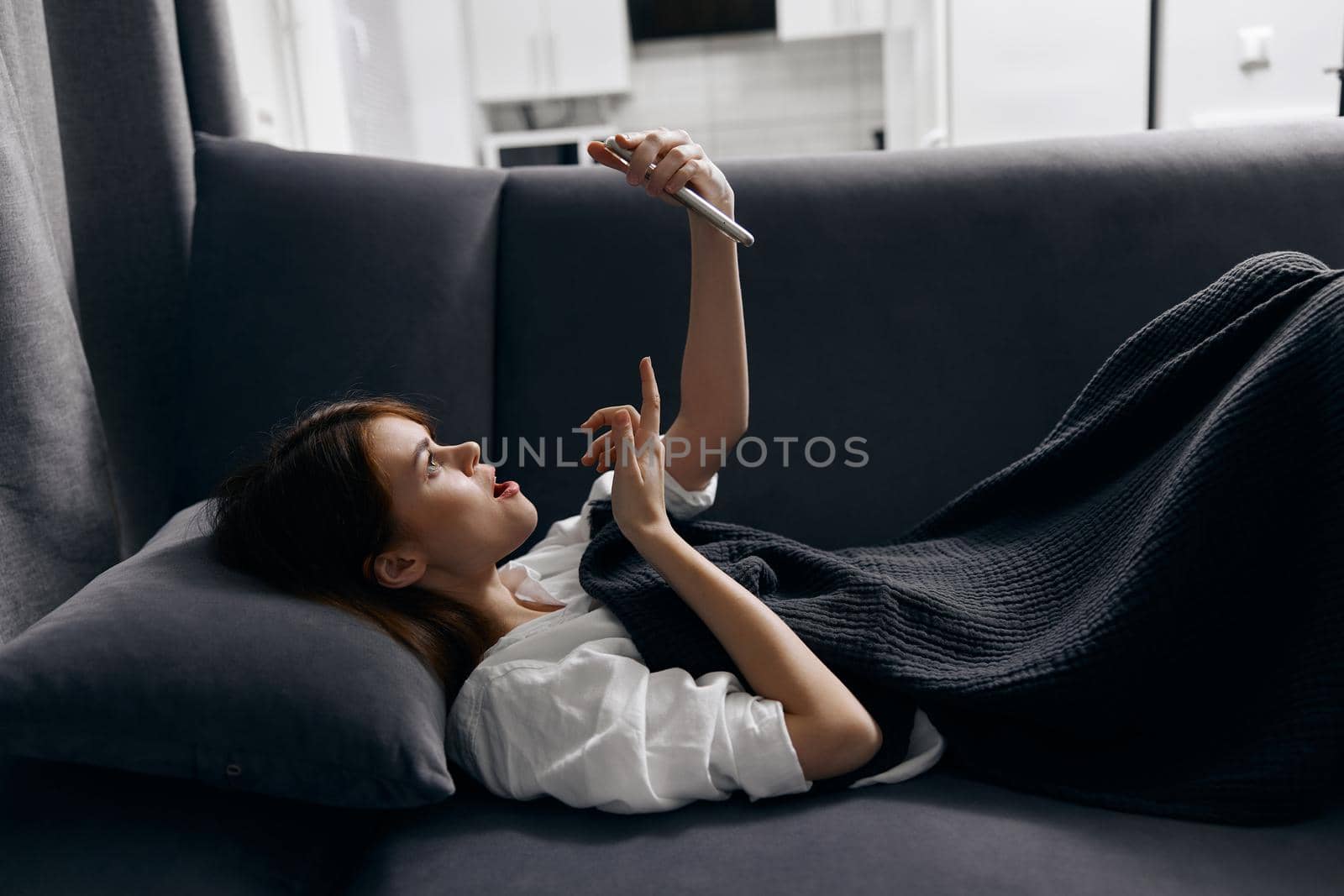 woman with mobile phone resting lying on the sofa indoors. High quality photo