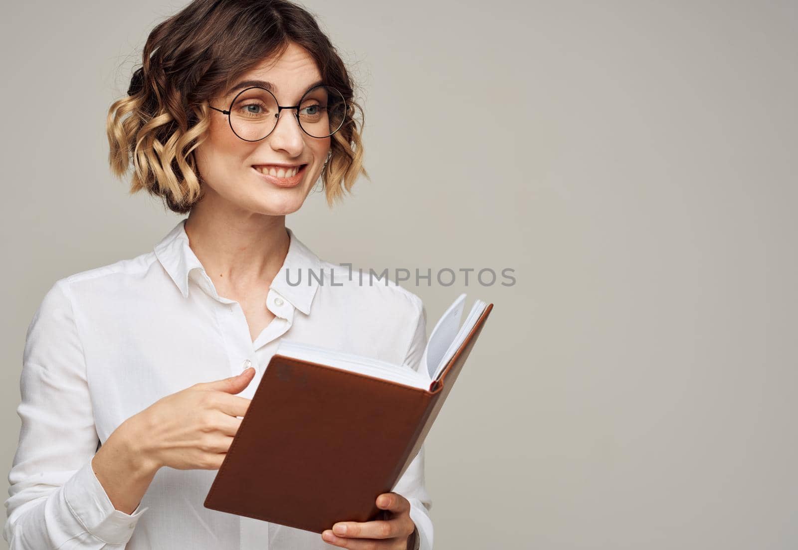 woman with notepad on gray background indoors gesturing with hands work office education. High quality photo