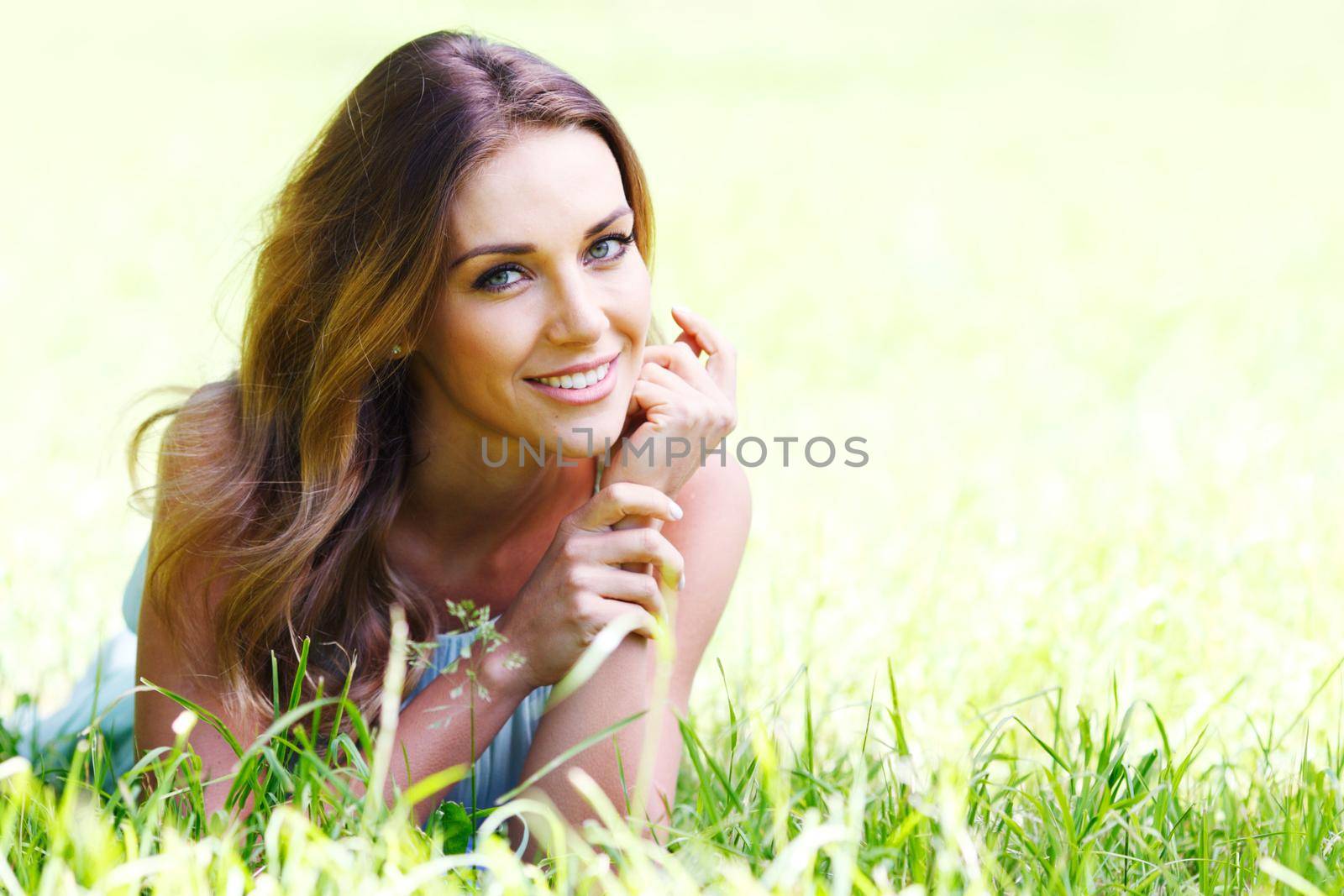 beautiful young woman in blue dress lying on grass