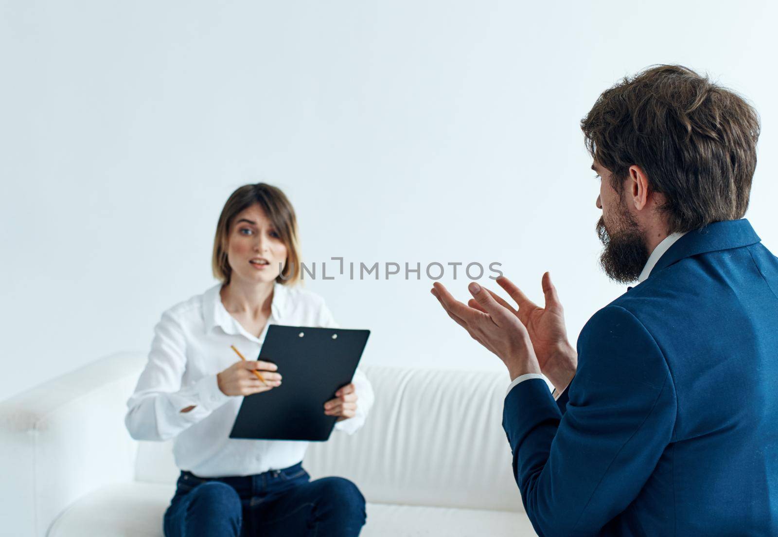 Business man in a classic suit and a woman on the couch with documents in the hands of a psychologist . High quality photo