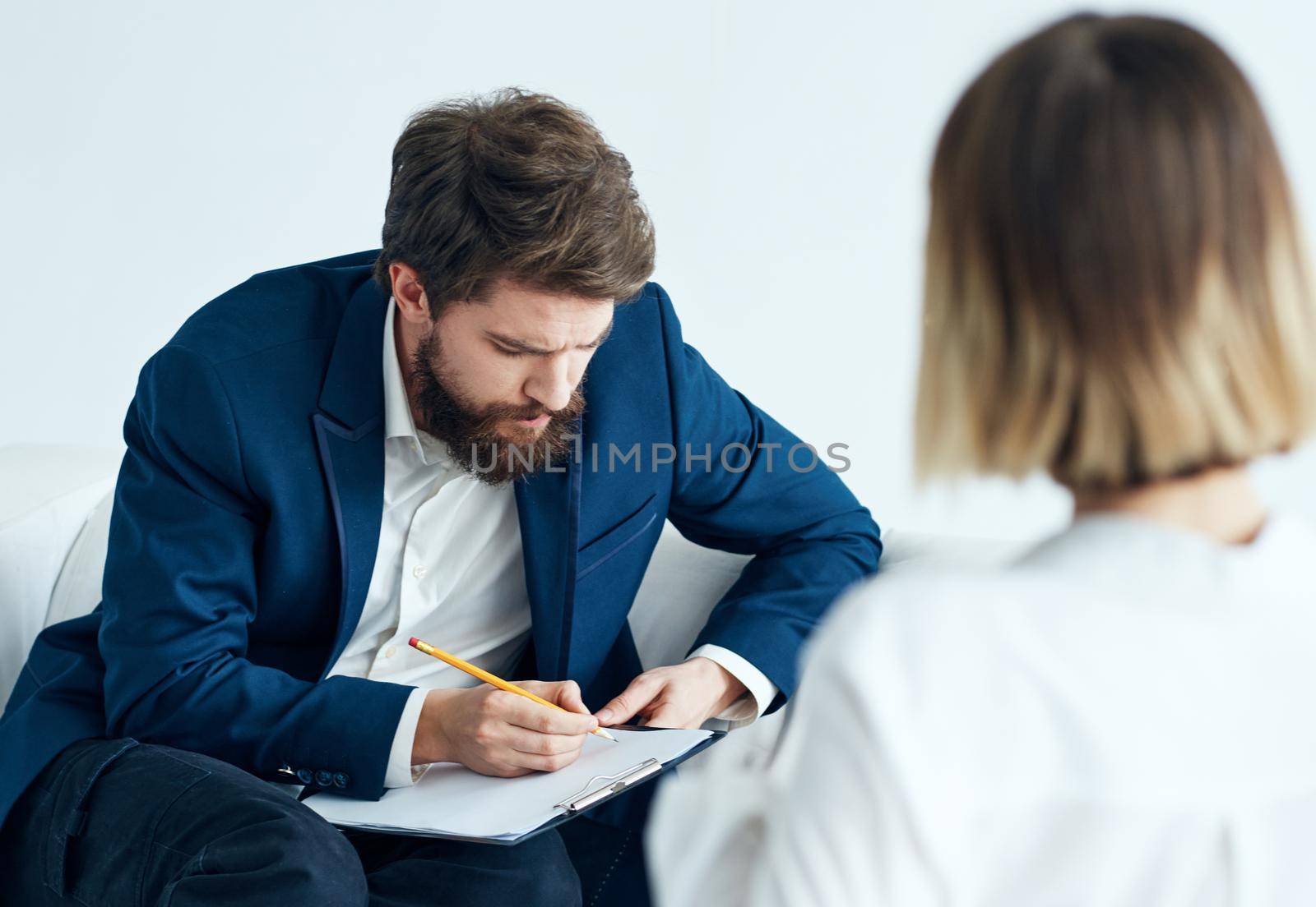 A man in a classic suit sits on the couch indoors with documents and a woman vacancy resume. High quality photo