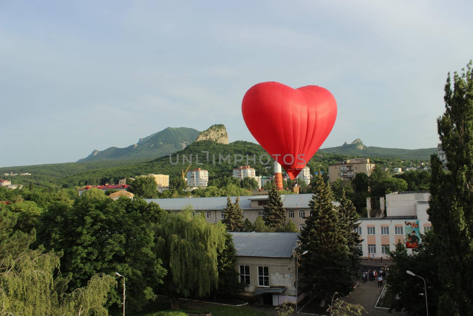 A red-hearted aerostat in the sky above the city. Romantic relationships. High quality photo