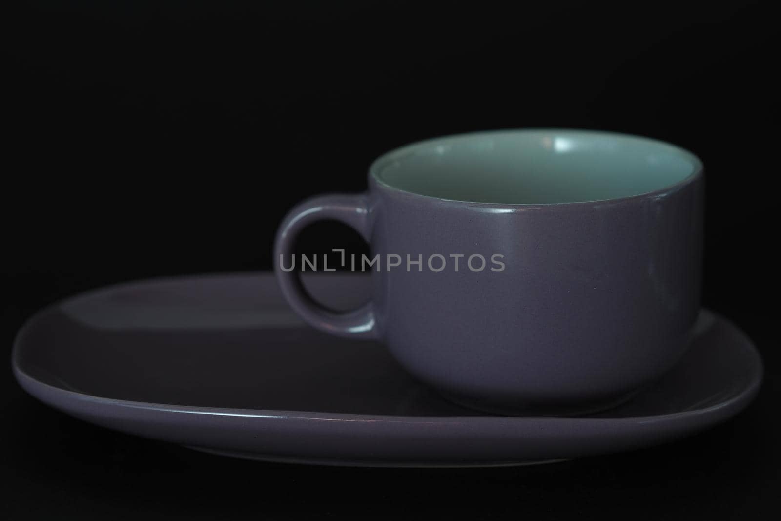 Tea cup with a saucer in the style of Provence on a black background. Purple on black.