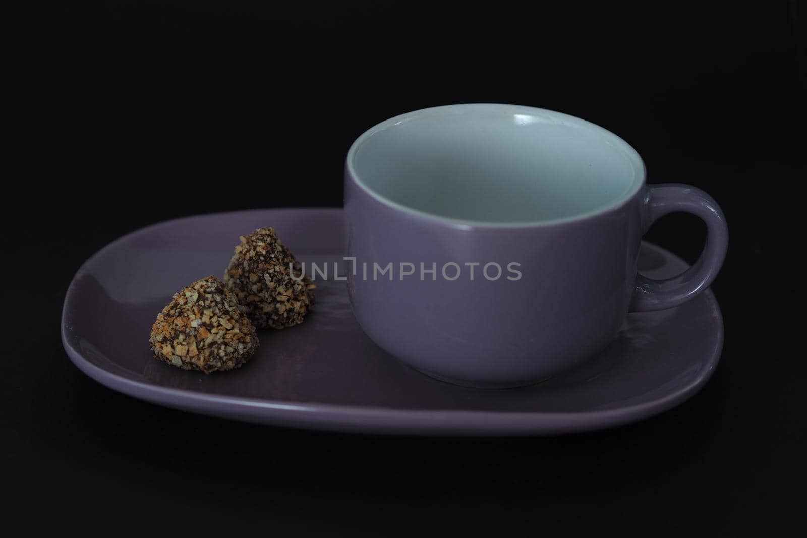 Tea cup with a saucer in the style of Provence on a black background. Purple on black.