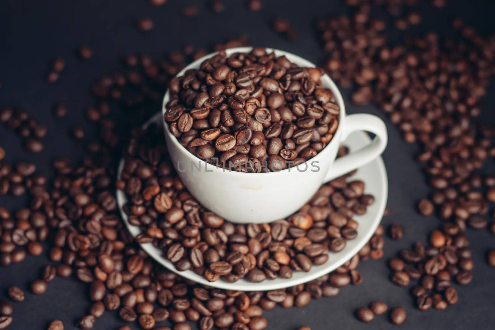 coffee beans In a saucer and in a cup of coffee on a gray background female hand macro photography. High quality photo