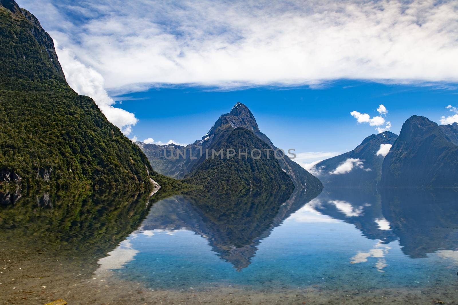 Famous Mitre Peak rising from the Milford Sound fiord and reflecting in water. Fiordland national park, New Zealand