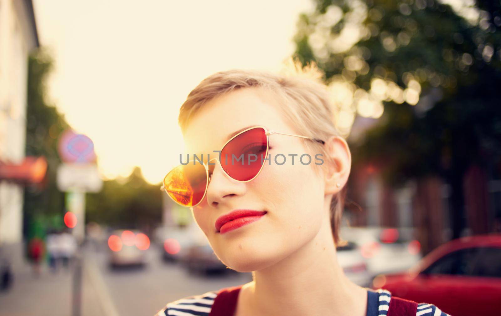 romantic woman in a sundress and red glasses walks along the city street in summer by SHOTPRIME