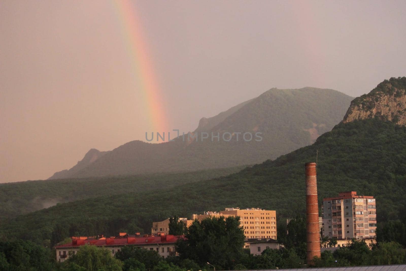 Rainbow over the city at sunset. Mountain landscape with a rainbow. Vertical image.