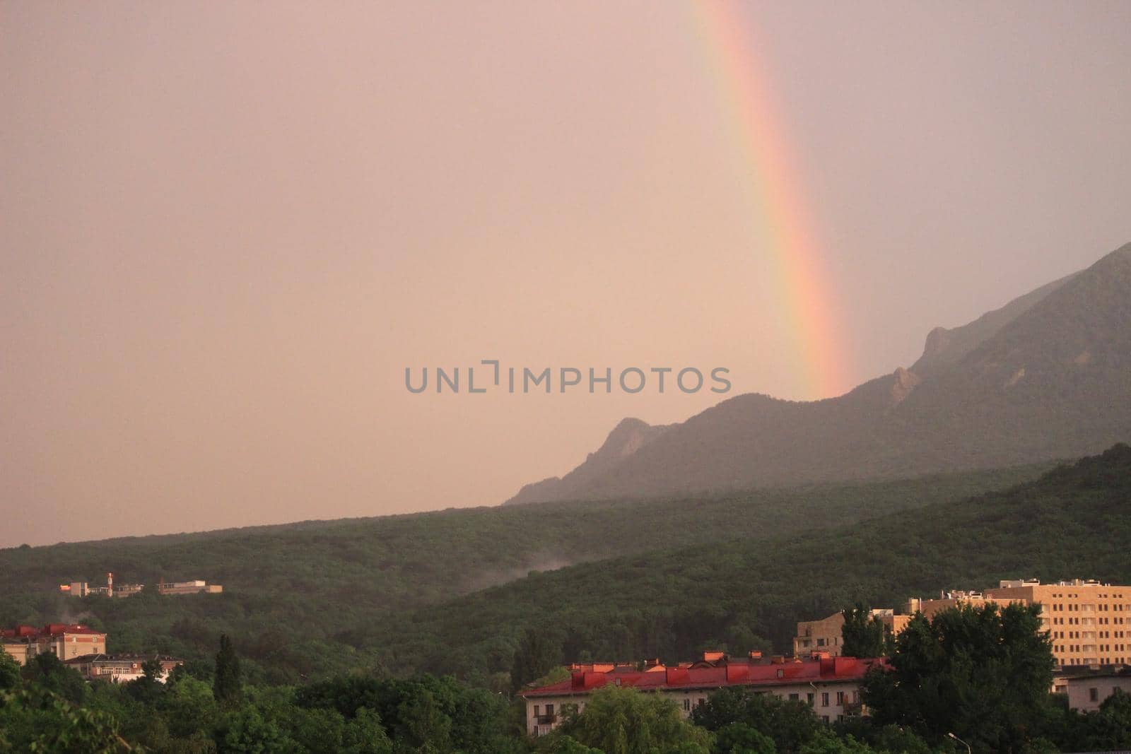 Rainbow over the city at sunset. Mountain landscape with a rainbow. by Olga26