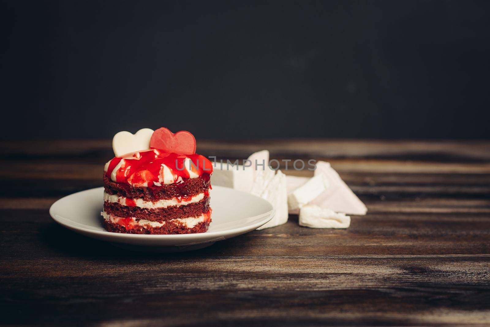 Round red cake on a plate marmalade sweets dessert wooden table. High quality photo