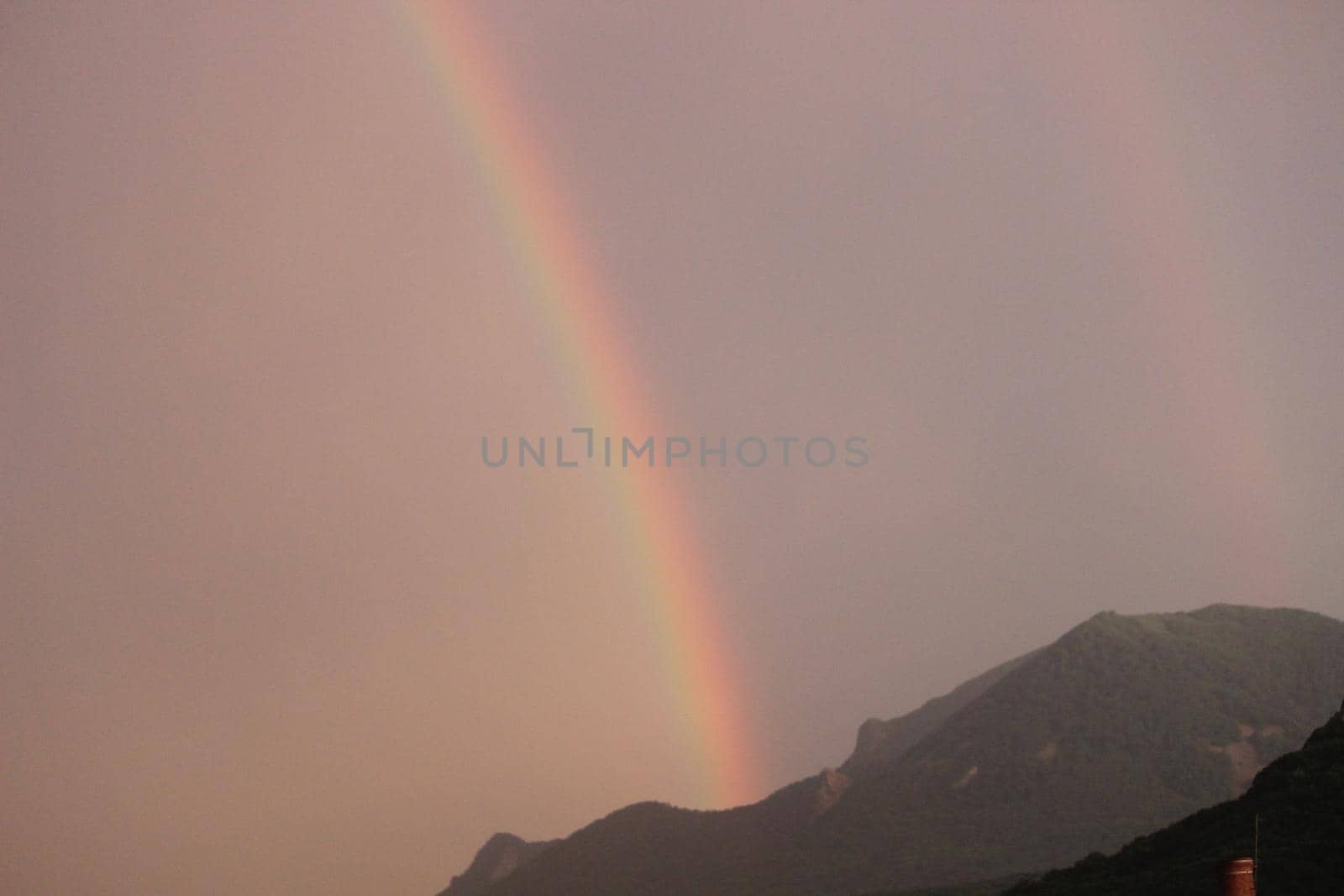 Rainbow over the city at sunset. Mountain landscape with a rainbow. by Olga26