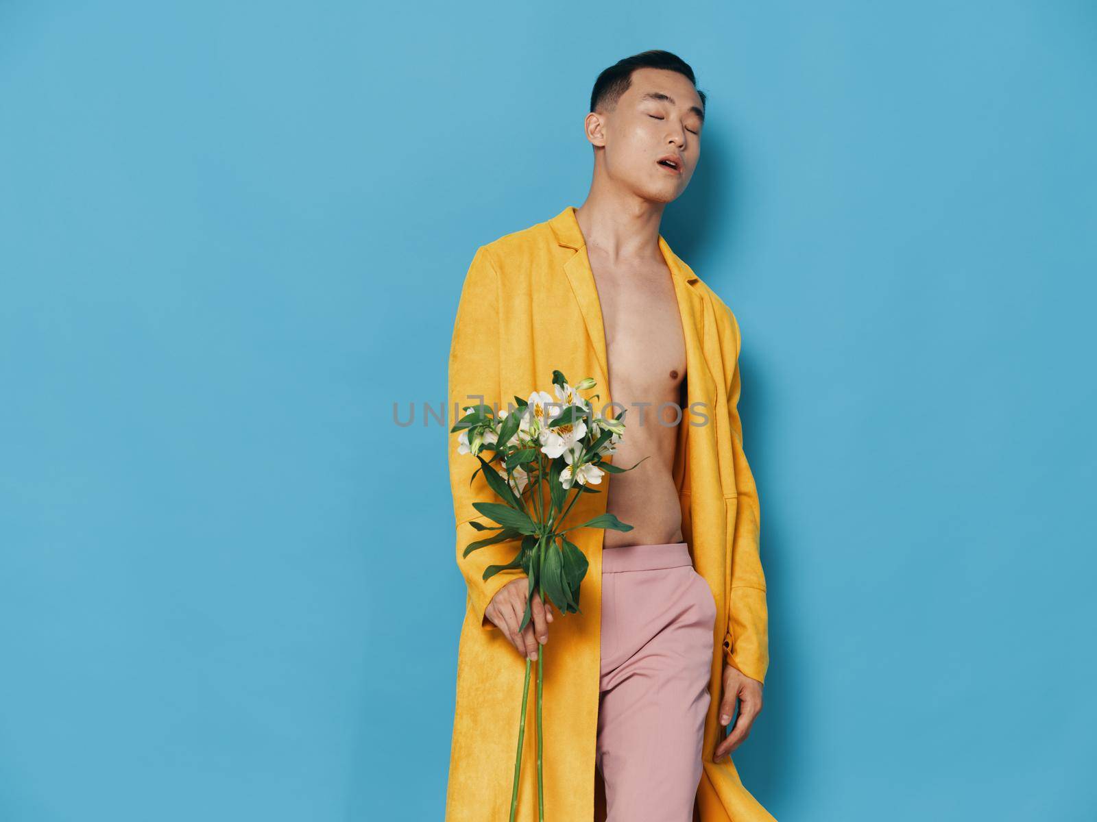 Romantic guy with a bouquet of flowers on a blue background in a yellow jacket cropped view. High quality photo