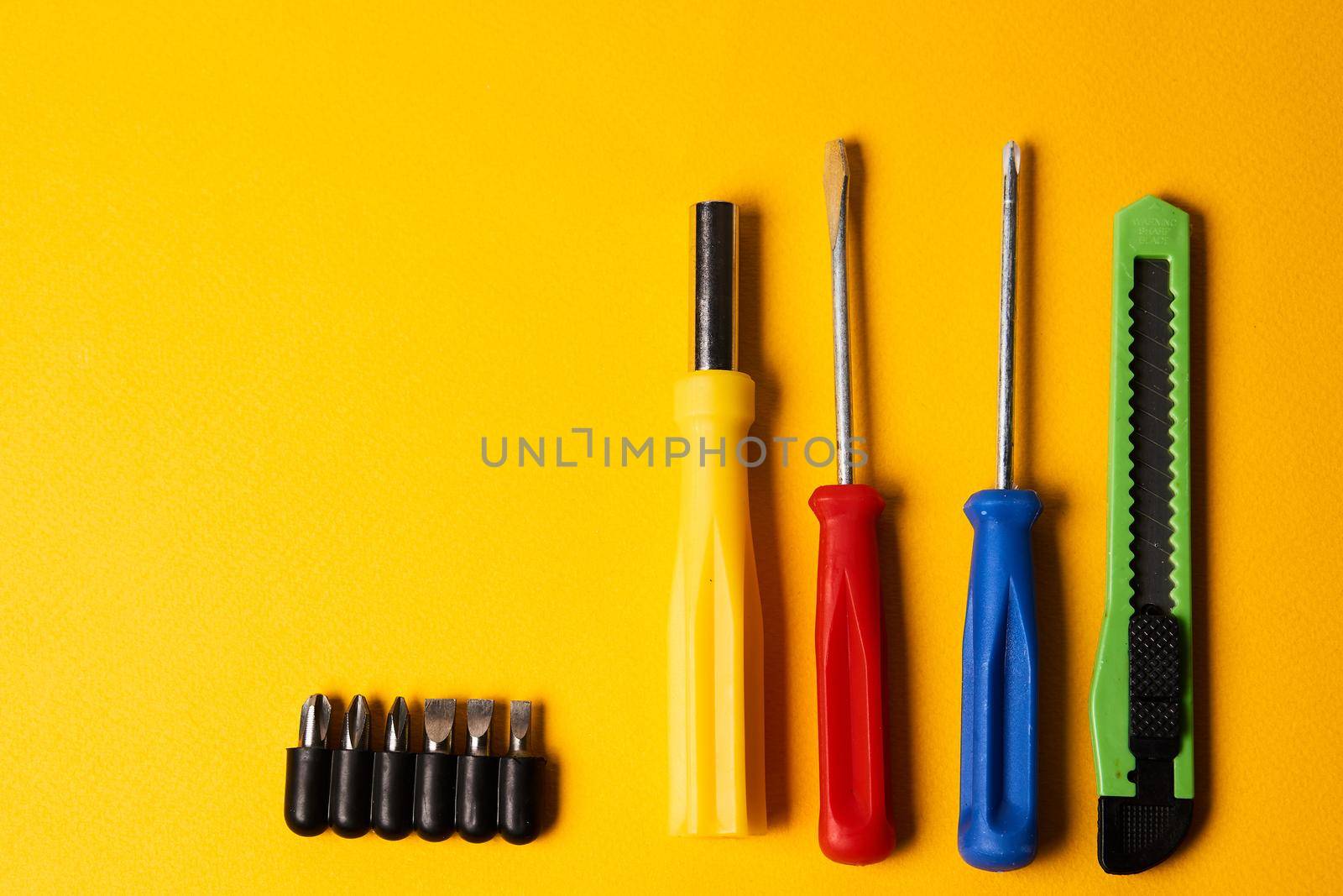 Construction tools screwdriver knives nozzles repair yellow background. High quality photo