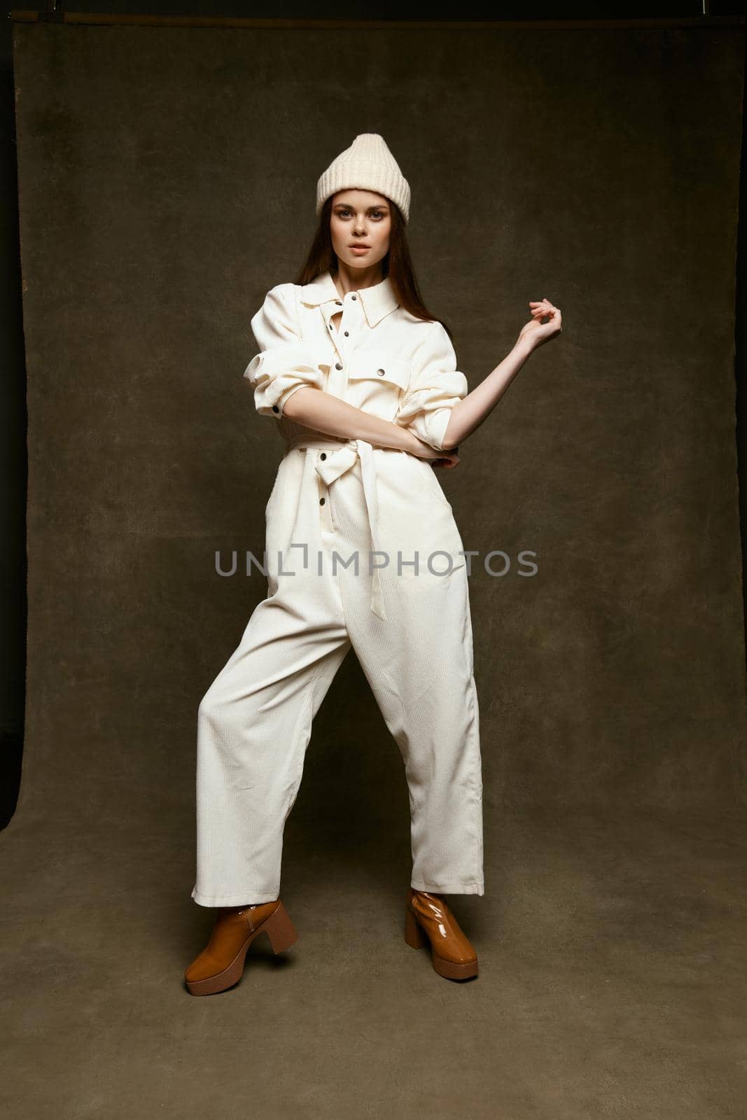Strong woman in a white hat and in a light suit on a brown background gestures with her hands Copy Space. High quality photo