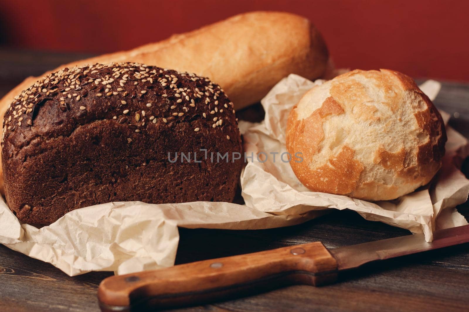 loaf of rye bread and flour products on paper packaging knife on a wooden table and red background. High quality photo