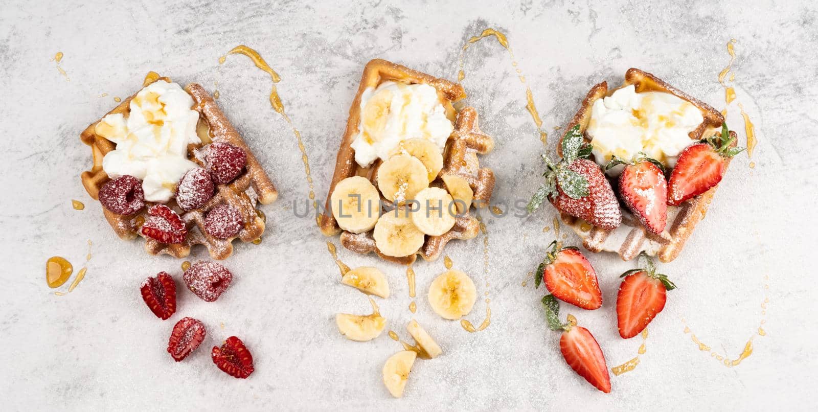 Traditional Belgian waffles with fresh fruit and cream on a white concrete background. by Desperada