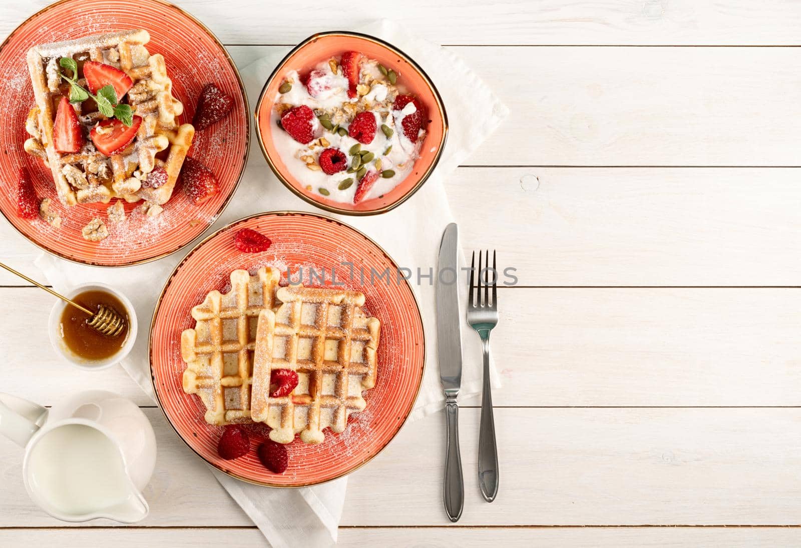 Flat lay of black plate with Belgian waffles with fresh stawberry on white wooden background. Flat lay, top view copy space.