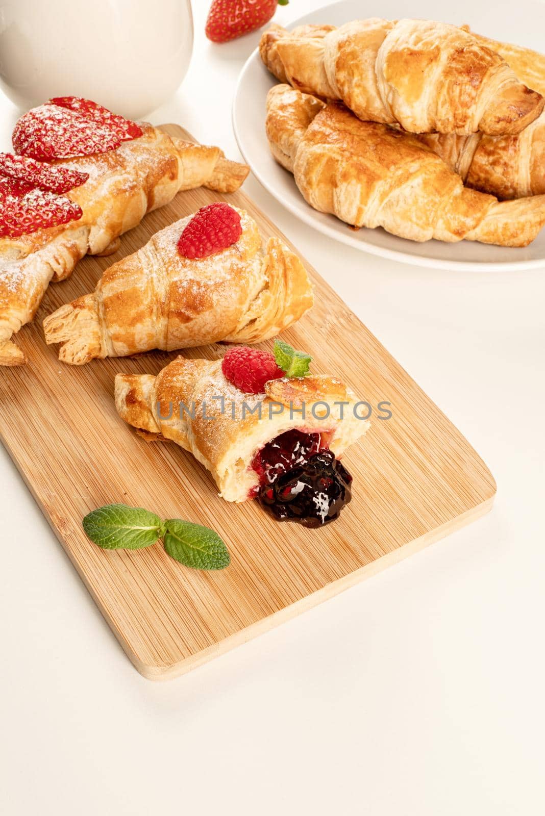 delicious golden croissants filled with strawberry jam on wooden board. Flat lay, top view