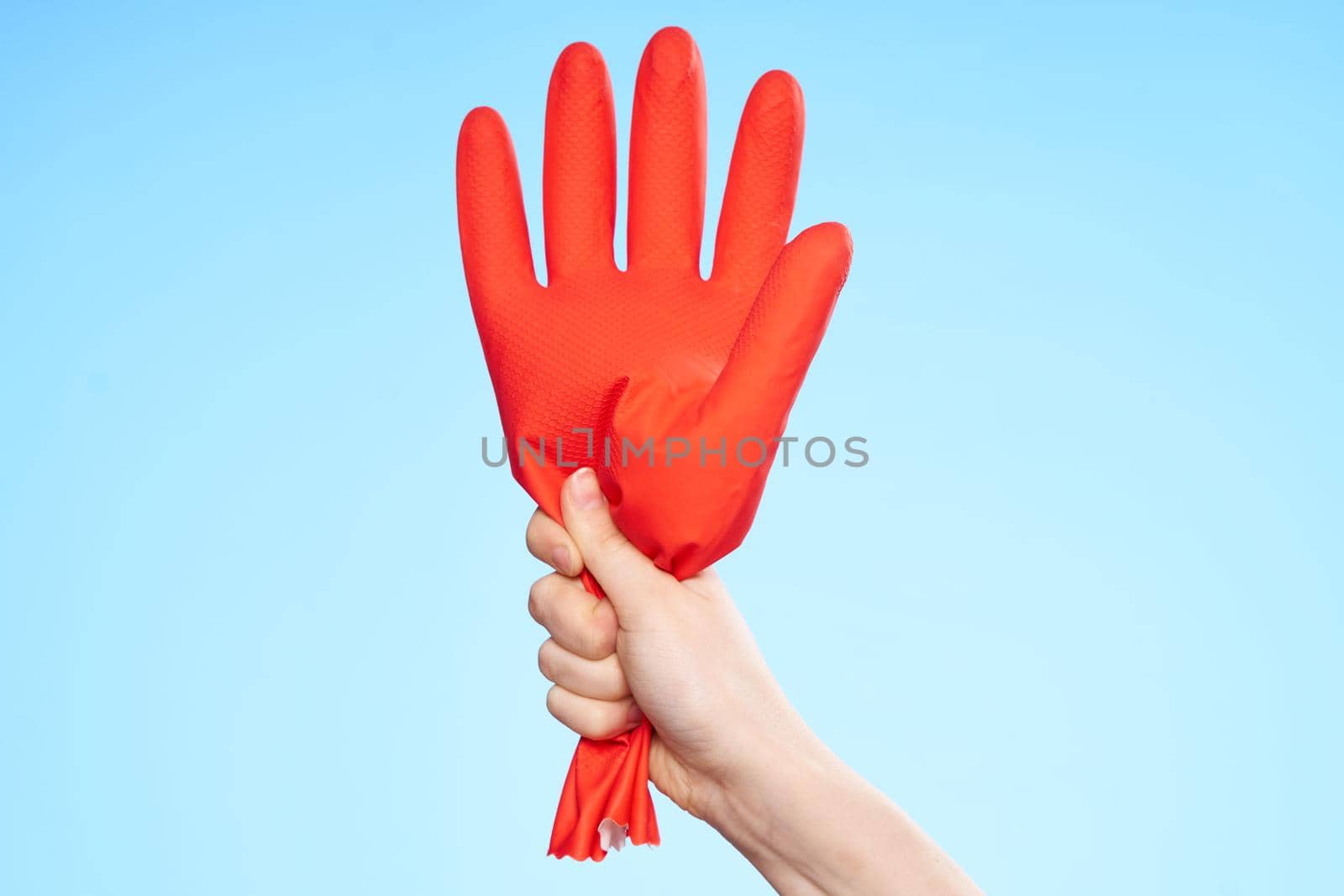 rubber glove in hand cleaning service blue background. High quality photo