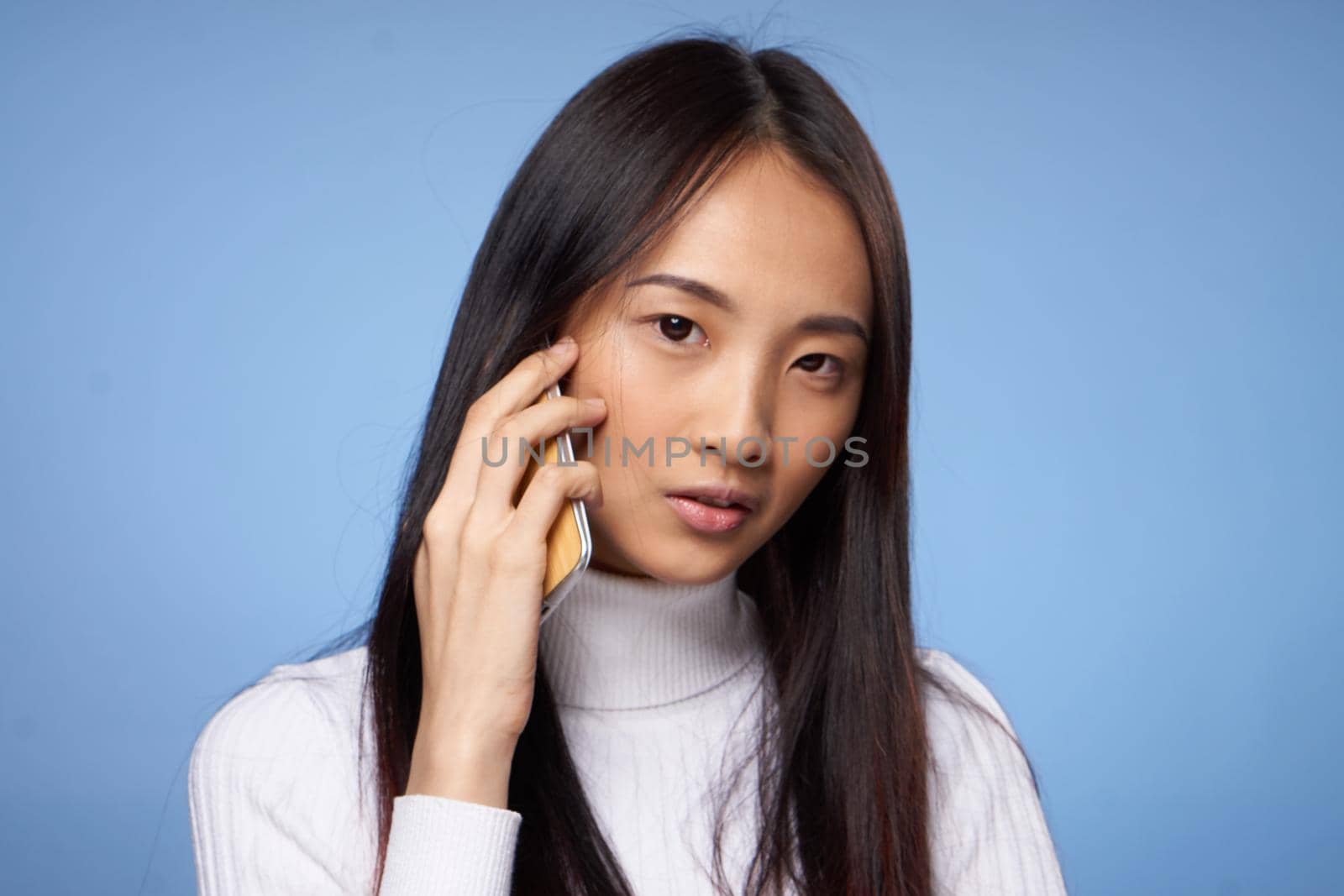 woman korean appearance talking on mobile phone on blue background. High quality photo