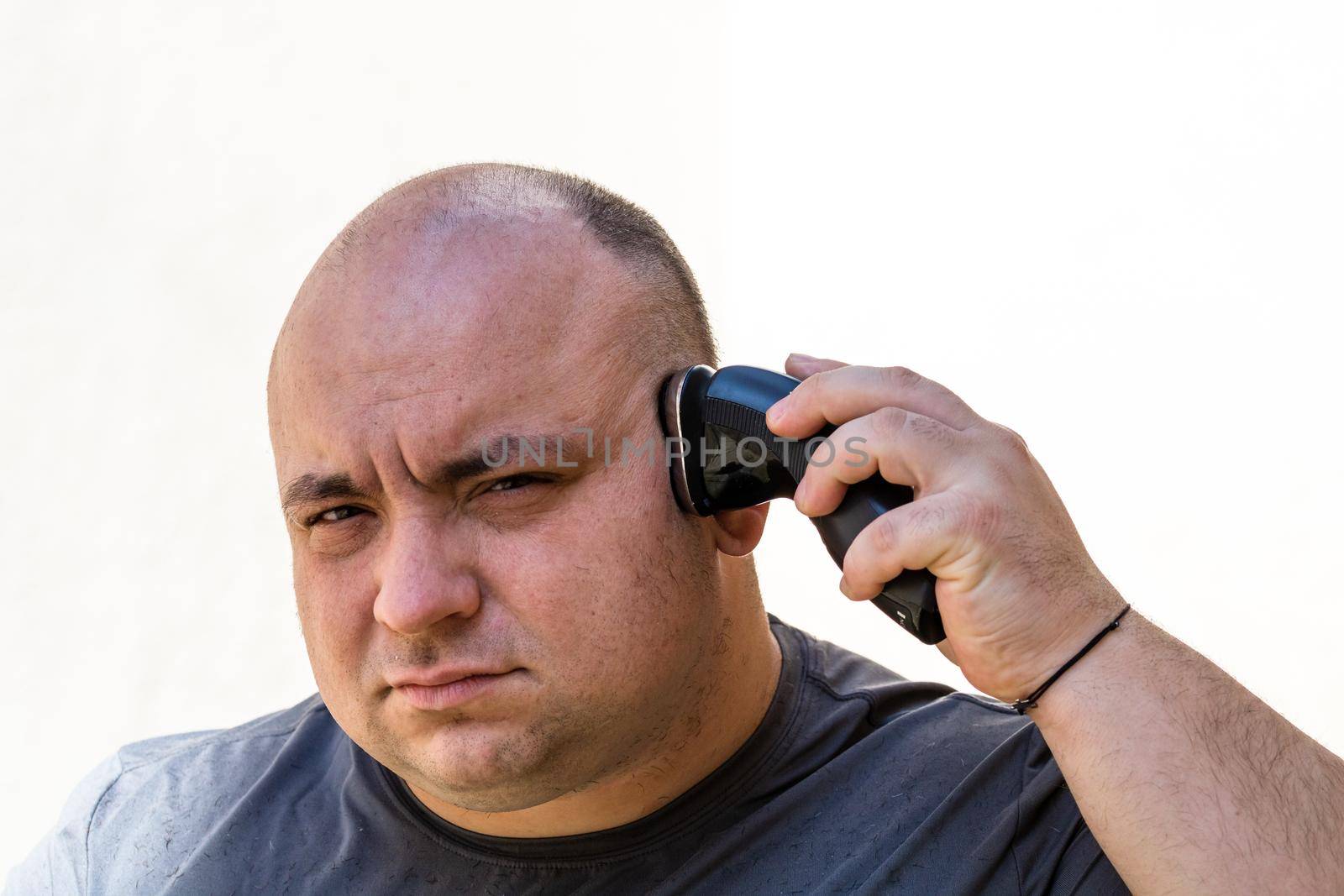 Male shaving or trimming his hair using a hair clipper or electric razor