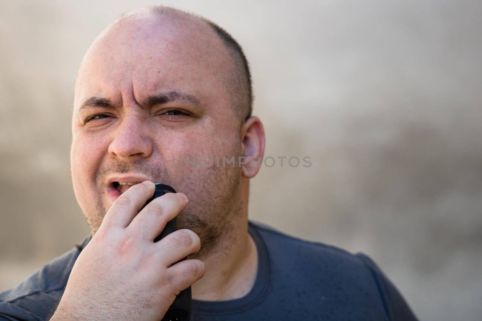 Male shaving or trimming his beard using a hair clipper or electric razor by vladispas