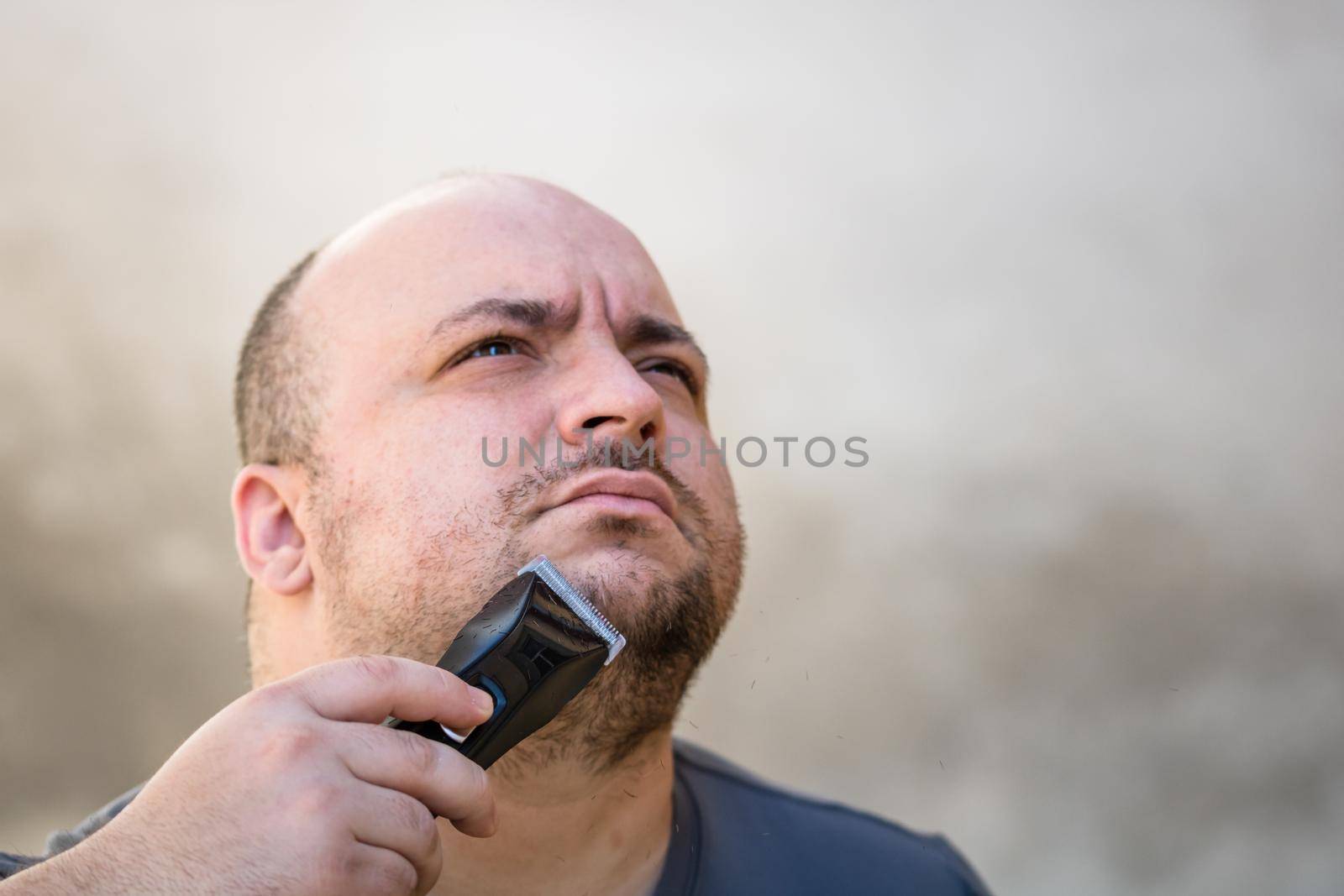 Male shaving or trimming his beard using a hair clipper or electric razor
