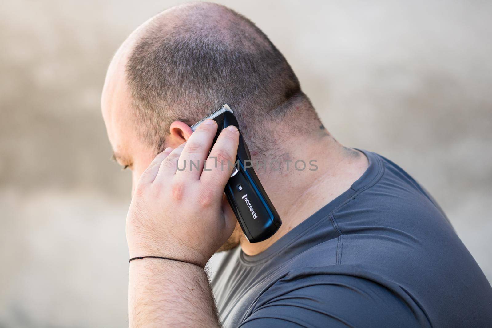 Male shaving or trimming his hair using a hair clipper or electric razor by vladispas