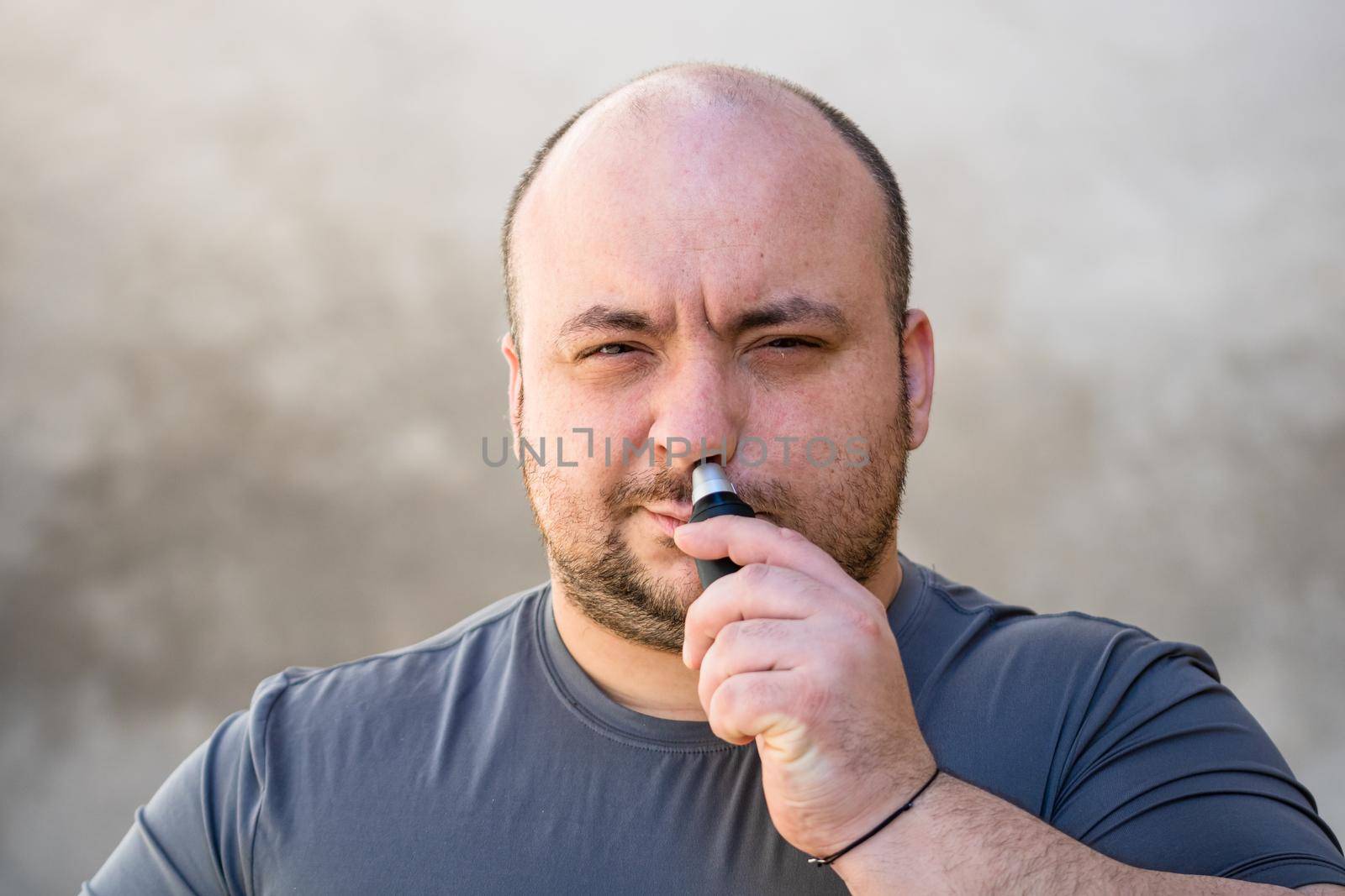 Male shaving ortrimming his nose hair using a hair clipper or electric razor