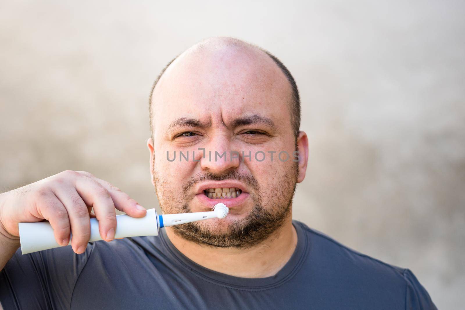 Male brushing his teeth with electric toothbrush by vladispas