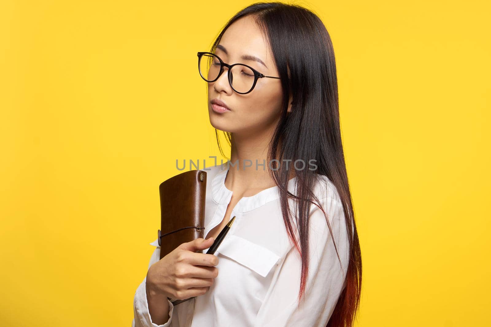 elegant woman holding notepad glasses manager executive yellow background. High quality photo