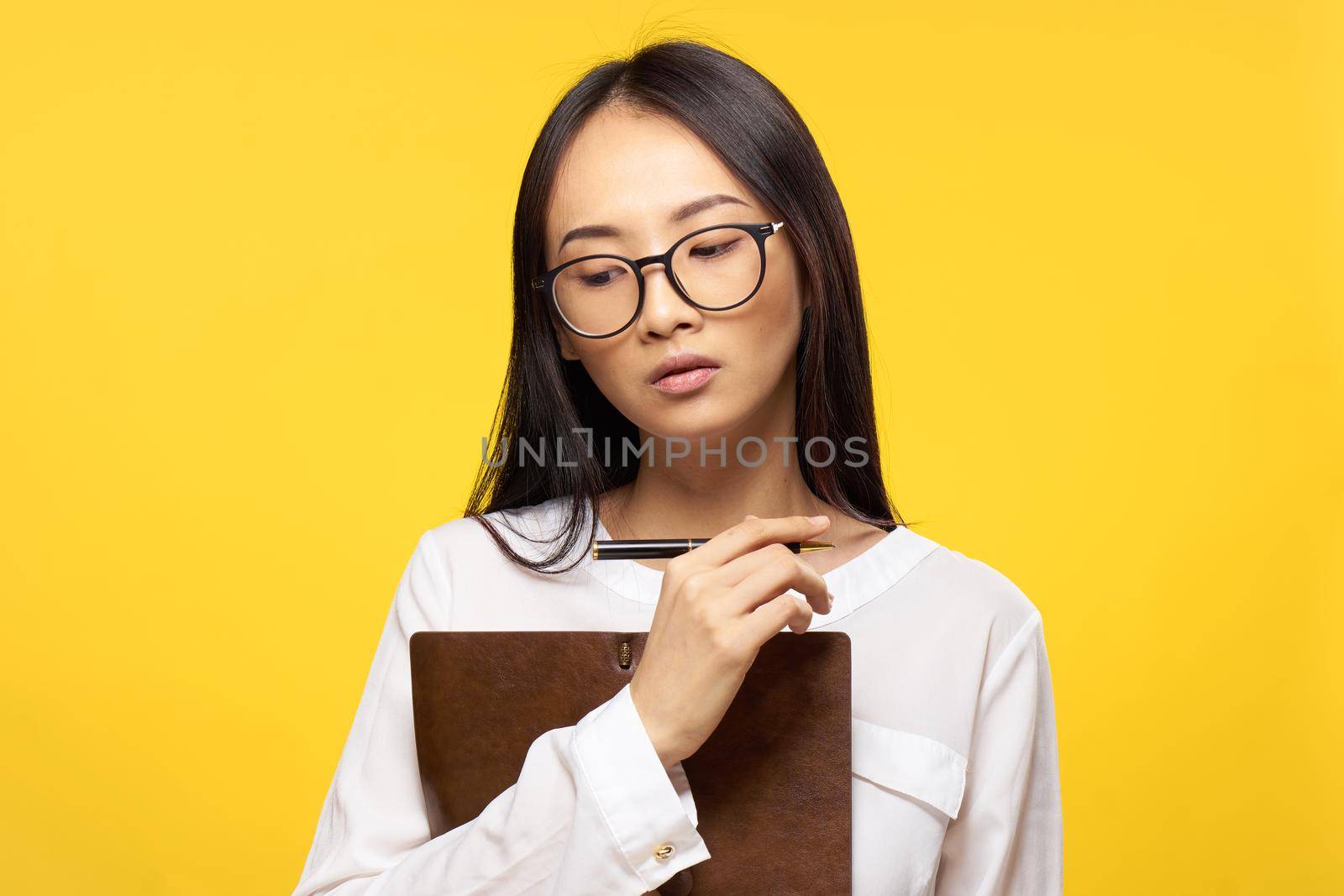 asian woman with notebook in hand learning student yellow background. High quality photo