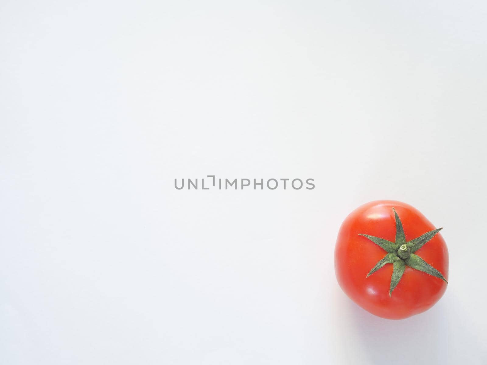 One red tomato on a white background is a close-up.