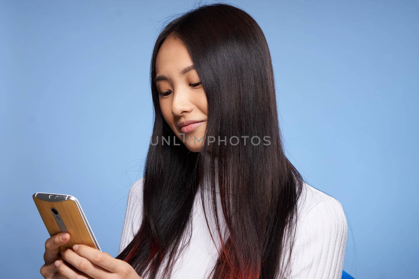 woman asian appearance phone hands communication technology lifestyle blue background. High quality photo