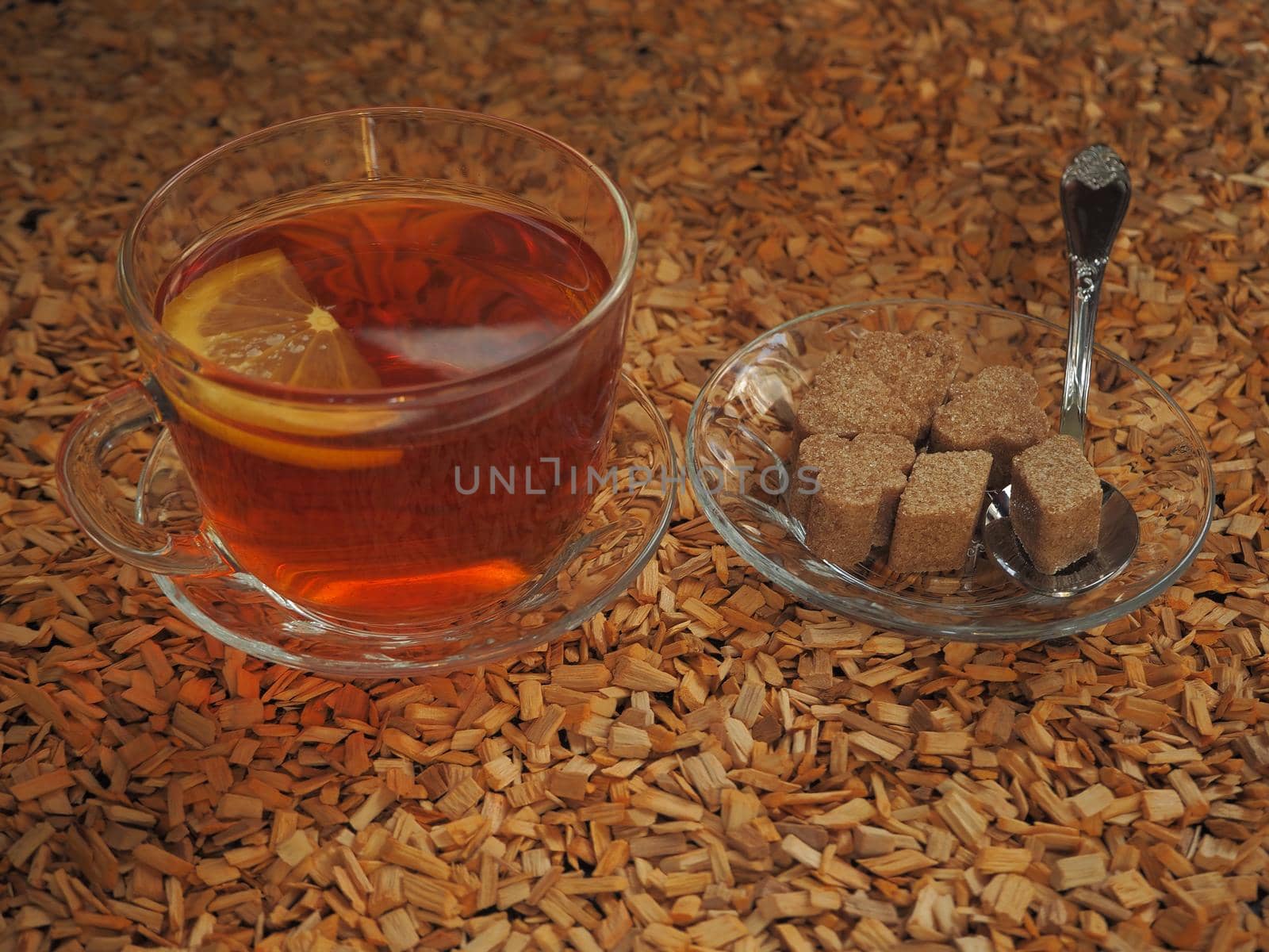 Black tea with lemon in a transparent cup on a wooden tray.